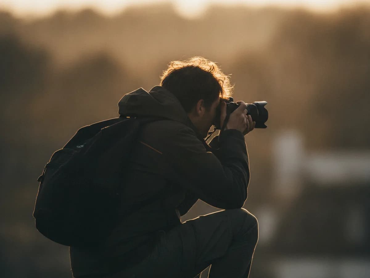 Fotograf kniet für die perfekte Perspektive, von hinten fotografiert
